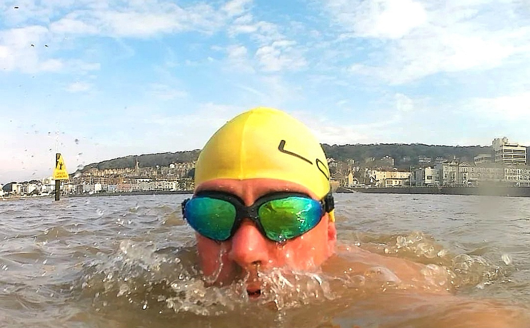 Male swimmer in goggles and yellow swimming hat in the sea